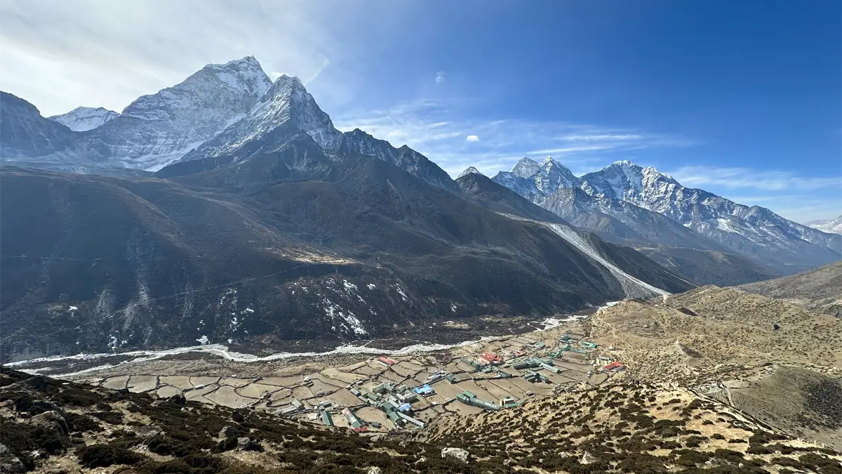 Trekkers on an acclimatization hike in Dingboche with Ama Dablam and the village in view on the Everest Base Camp trek
