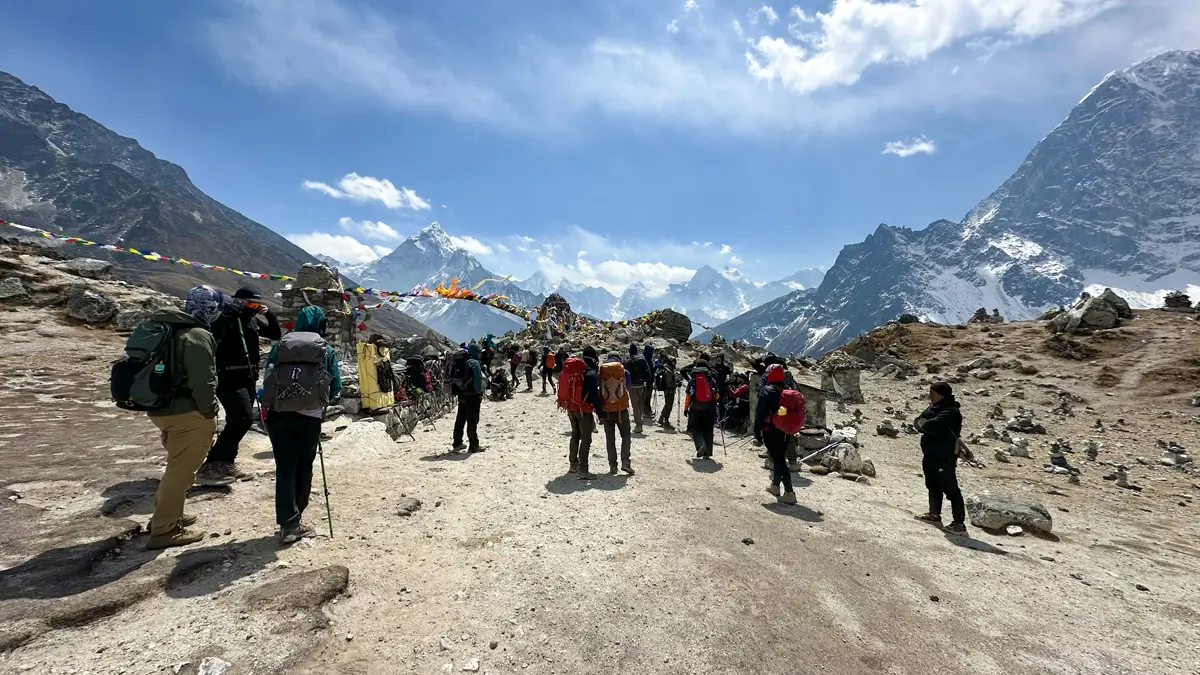 Many trekkers crossing Thukla Pass on the Everest Base Camp trek, with memorials visible along the trail