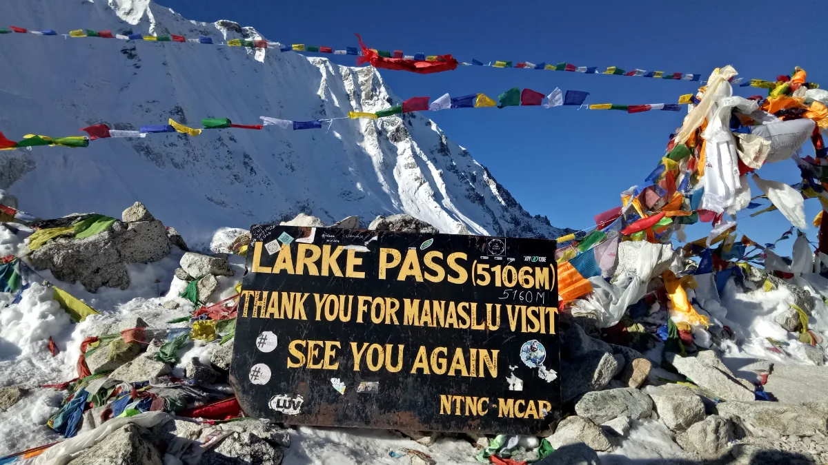 Larkya La Pass crossing at 5,160 meters highest point of Manaslu Circuit trek with prayer flags